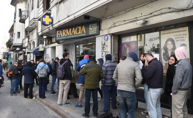 Pictured: Customers wait in line for cannabis at a Uruguay pharmacy.